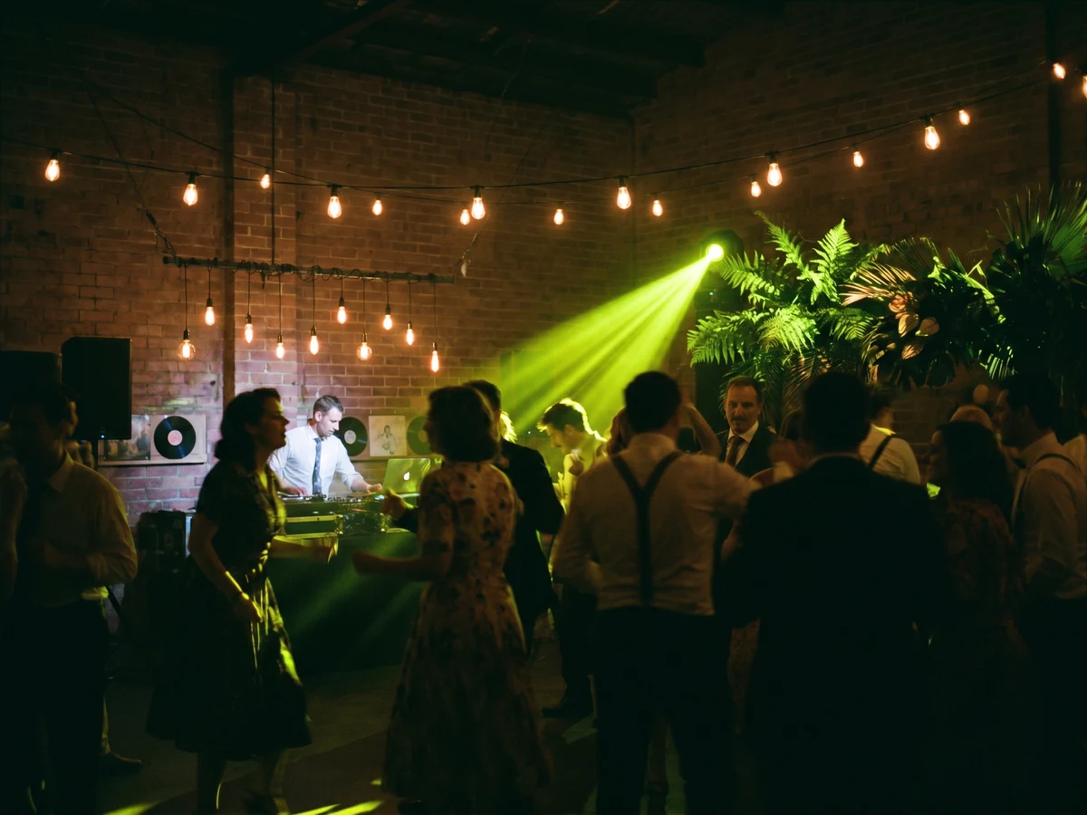 A late-night dancefloor lit by warm bulbs and a green spotlight